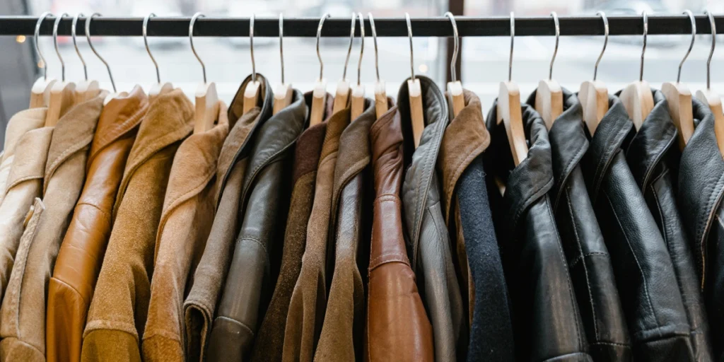 A clothing rack filled with assorted leather and suede jackets in various shades of brown and black.